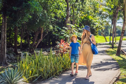 Expectant mother and her son enjoying a leisurely stroll in the park, cherishing precious moments amidst nature's beauty.