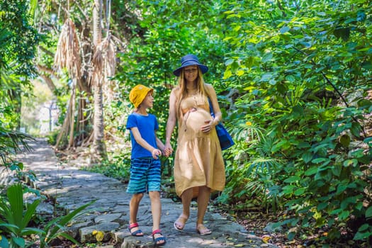 Expectant mother and her son enjoying a leisurely stroll in the park, cherishing precious moments amidst nature's beauty.