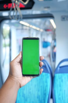 young man hand using smart phone with green screen inside of metro train ,