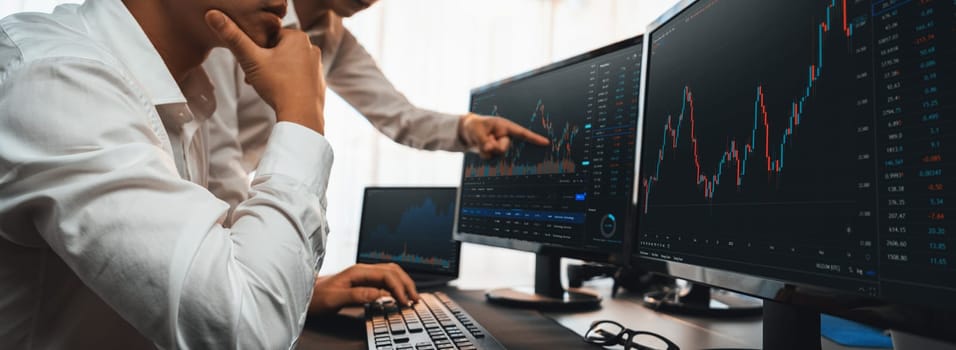 Group of traders discussing on office desk, monitoring stock market on monitor at office workplace. Businessman and broker analyzing stock graph together at stock trading company. Trailblazing