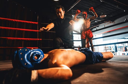 Boxing referee intervene, halting the fight to check fallen competitor after knock out. Referee pauses the action for boxer fighter's safety after KO with winner posing in background. Impetus
