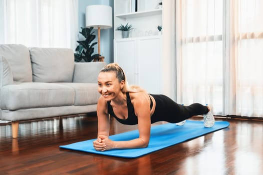 Athletic and sporty senior woman planking on fitness exercising mat at home exercise as concept of healthy fit body lifestyle after retirement. Clout