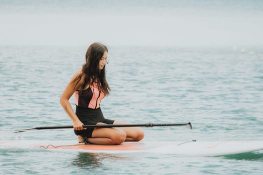 Close up shot of beautiful young caucasian woman with black hair and freckles looking at camera and smiling. Cute woman portrait in a pink bikini posing on a volcanic rock high above the sea