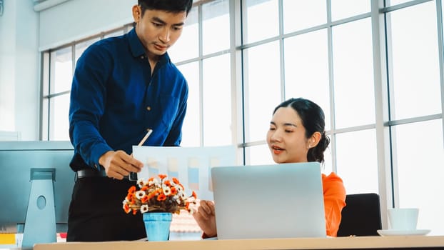 Two business people talk project strategy at office meeting room. Businessman discuss project planning with colleague at modern workplace while having conversation and advice on financial report. Jivy