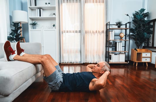 Athletic and active senior man using furniture for effective targeting muscle with situp at home exercise as concept of healthy fit body lifestyle after retirement. Clout