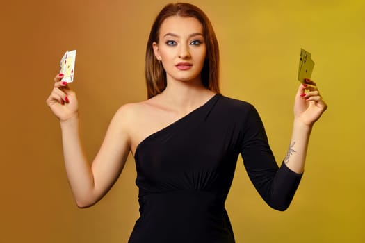 Alluring blonde woman with bright make-up, red manicure, in black dress is showing four playing cards, posing against colorful background. Gambling entertainment, poker, casino. Close-up.