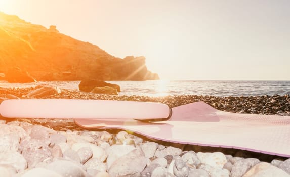 Young woman with long hair in white swimsuit and boho style braclets practicing outdoors on yoga mat by the sea on a sunset. Women's yoga fitness routine. Healthy lifestyle, harmony and meditation