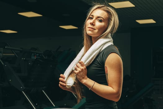 Young woman with towel sitting and resting in a gym