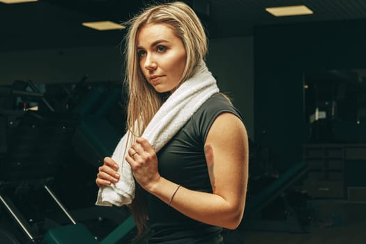 Young woman with towel sitting and resting in a gym