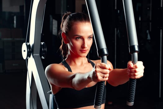 Young attractive woman doing exercises for arms in a training machine