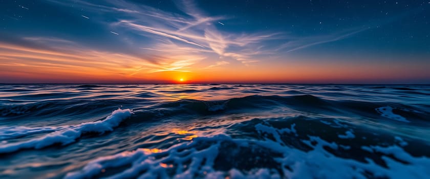 The horizon glows with vibrant colors as the sun sets over the ocean, casting reflections on the water's surface while gentle waves lap the shore.