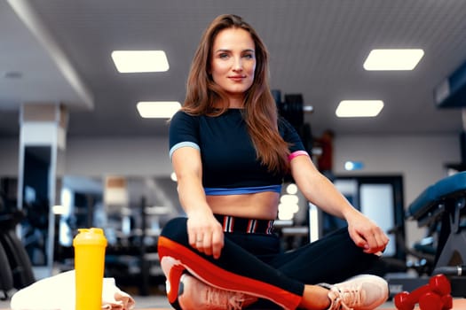 Woman fitness trainer portrait on a gym background