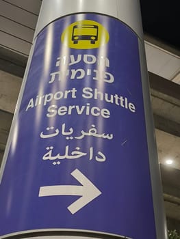 18 August 2024 Tel-Aviv Israel Ben Gurion airport sign arrow movement to shuttle, transport signal, in three languages, English, Hebrew, Arabic. High quality photo