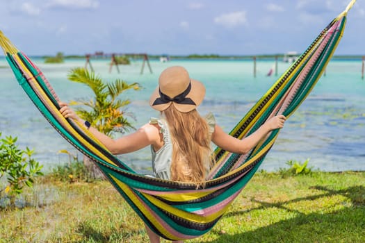 Female tourist sitting in hammock against background of turquoise waters of Lake Bacalar. Family bonding, summer vacation, and outdoor fun in Quintana Roo, Mexico concept.
