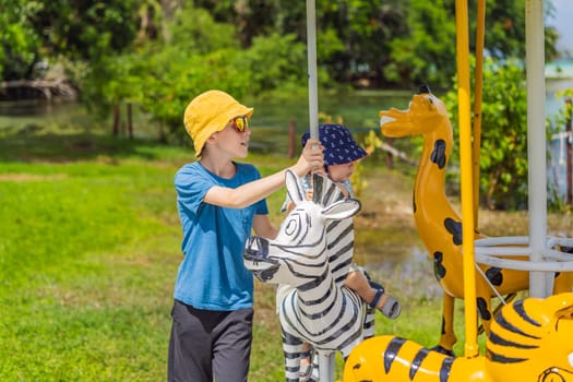 a little boy is a blonde child with his older brother in an amusement park, riding on a carousel, smiling, rejoicing.