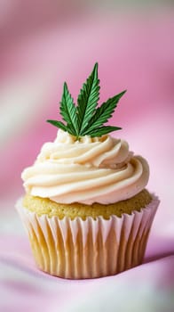 Cupcake with cannabis leaf on pink background, creative dessert concept.
