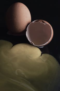 View of Broken egg yolk with Broken raw chicken eggshell in front of Fresh chicken egg (Hen eggs) on Dark background. Fresh eggs from the farmer, Natural organic healthy food concept, Copy space, Selective focus.