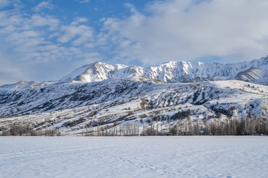 winter landscape with Tien Shan mountains in Kazakhstan in snow under a blue sky with clouds
