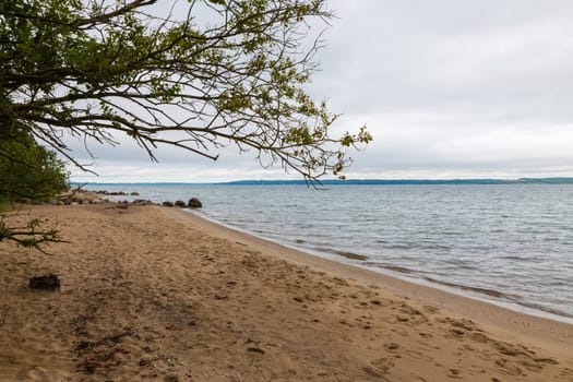 rocks and sand on a beach in denmark with no people , horizon and the kattegat water
