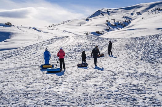 People relax in nature and ride downhill on tubing during the winter holidays. Shymkent, Kazakhstan - January 27, 2024