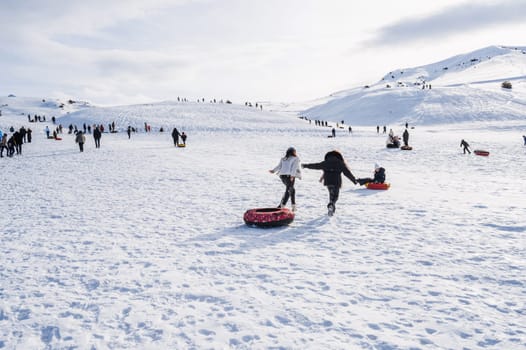 People ride downhill on tubing in winter outdoors on active recreation in mountains in nature. Shymkent, Kazakhstan - January 27, 2024