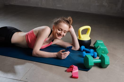 sporty woman after workout chatting on phone in gym, fitness trainer feeds online workout, love for sports concept