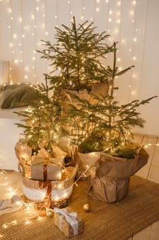 Designer Christmas tree decoration with light decorations. The concept of celebrating New Year and Christmas. Gifts in craft packaging under the Christmas tree.