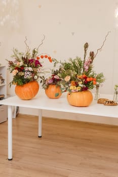 Flower arrangement in a pumpkin, autumn interior decor. Creating handmade autumn decor