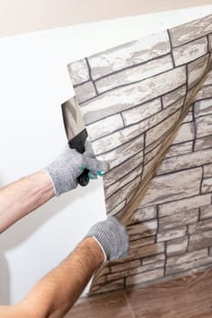 woman tears off Wallpaper, removing Wallpaper from the wall with a spatula, the process of updating the wall room repair.