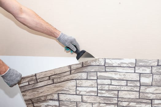 woman tears off Wallpaper, removing Wallpaper from the wall with a spatula, the process of updating the wall room repair.