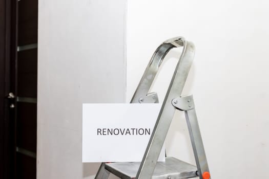 Stepladder and painting tools near wall in empty room