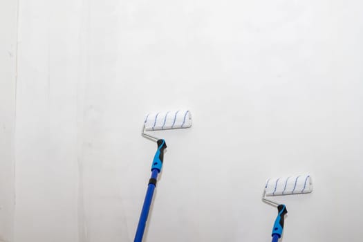 Male hand painting wall with paint roller. Painting apartment, renovating with white color paint