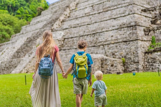 Mother with her toddler and teenage sons exploring the ancient pyramids of Palenque, Mexico, surrounded by dense jungle. Cultural heritage and adventure travel concept.
