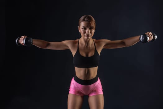 sporty girl doing exercises with dumbbells on black background, sport concept, healthy and beautiful body