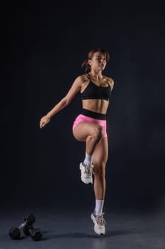 sporty girl doing exercises with dumbbells on black background, sport concept, healthy and beautiful body