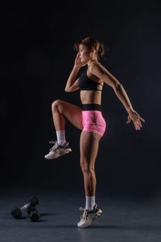 sporty girl doing exercises with dumbbells on black background, sport concept, healthy and beautiful body