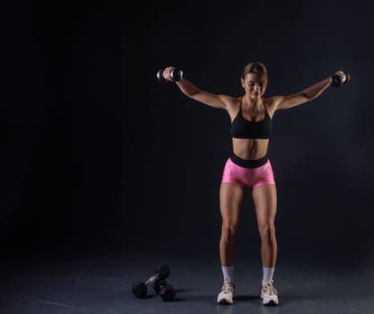 sporty girl doing exercises with dumbbells on black background, sport concept, healthy and beautiful body