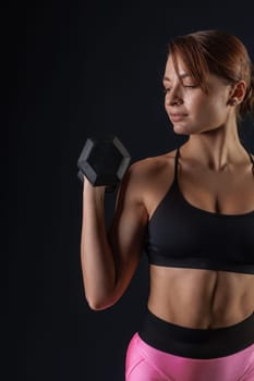 sporty girl doing exercises with dumbbells on black background, sport concept, healthy and beautiful body