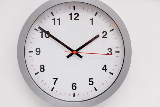 Simple modern wall clock in silver color frame, isolated on white background