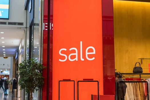 Inscription Sale on the background of a red glass wall in the store. Mall Discount Announcement. Summer, winter Christmas, New Year sale