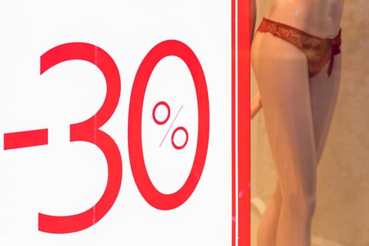 Discount percentage sign display in fashion department store during sale season period.