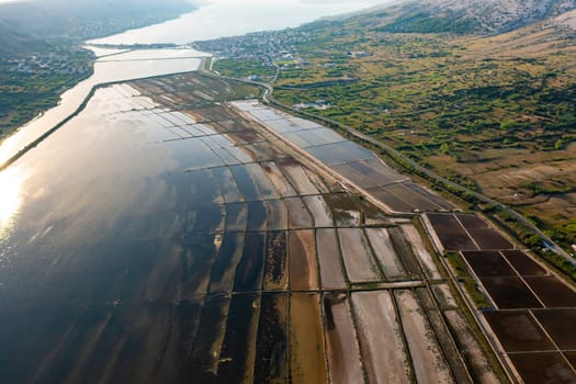 Aerial view of salt pans at sunset showcasing seawater evaporation and salt production