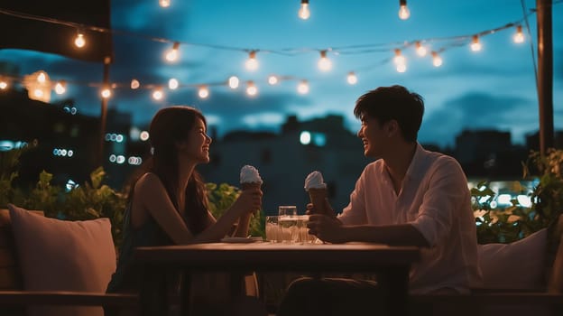 A couple shares smiles and ice cream while seated at a table on a rooftop terrace as dusk settles in.