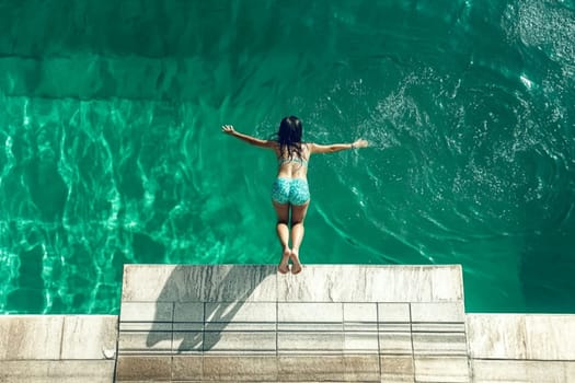Young woman is taking a refreshing dip in the crystal clear turquoise water, her arms outstretched as she enjoys a moment of pure joy and freedom