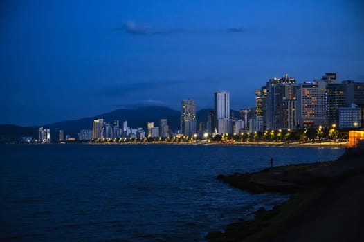 The promenade by the sea with a view of skyscrapers and hotels at night. Panorama of Nha Trang city in Vietnam