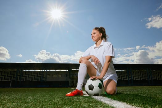 girl Football player in white shorts and red boots standing with soccer ball on green artificial turf field. women football concept