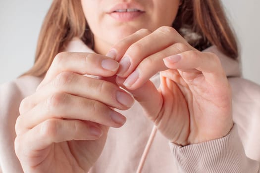 Onychophagy. A nervous young woman is biting her nail due to stress and anxiety. Concept of anxiety, stress, bad habits, mental health