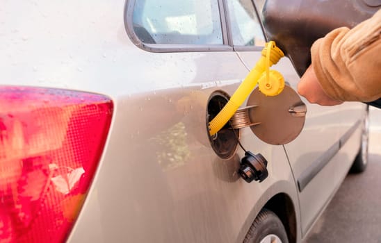 A man filling the fuel tank of his car with diesel fuel from the jerry can as there is no fuel at the petrol station, close up. The fuel crisis is continue