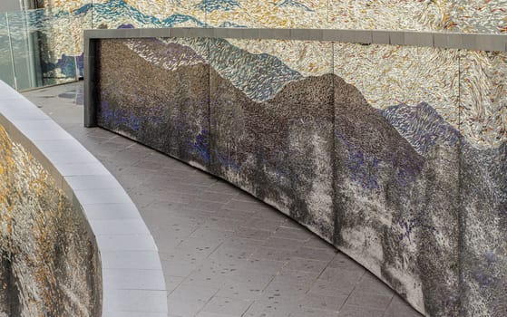 Bangkok, Thailand - 28 Sep, 2024 - A sloping walkway leading down to a park in a high-rise building with cladding in the shape of an arch are decorated with colorful Stained glass scraps mosaic.Space for text, Selective focus.