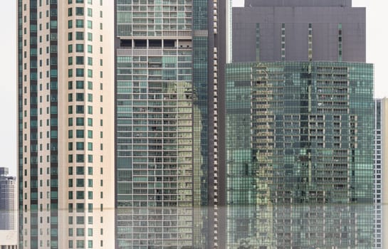 Bangkok, Thailand - 28 Sep, 2024 - Architectural exterior of modern office building facade with blue sky and clouds reflection in windows. Steel frame and glass windows architecture, Space for text, Selective focus.